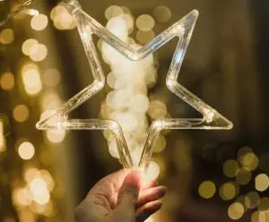 A hand holds up an LED lights Christmas star with more lights behind the star